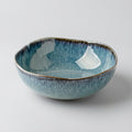 Blue glaze ceramic irregular soup bowl on clean studio background
