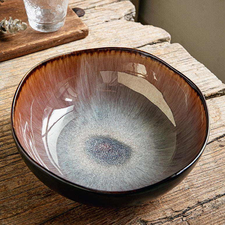 Retro ceramic irregular soup bowl in flame glaze finish closeup on wooden table
