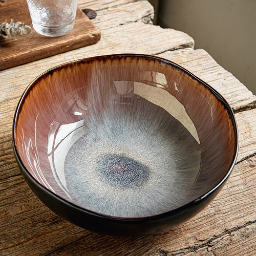 Retro ceramic irregular soup bowl in flame glaze finish closeup on wooden table
