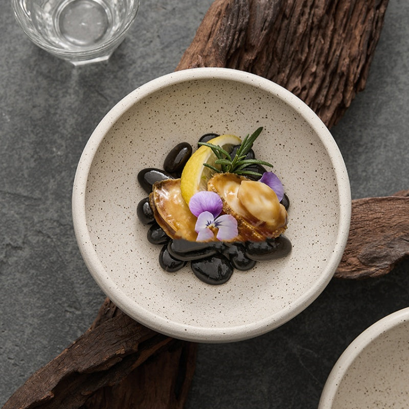 Sesame glazed ceramic conical bowl overhead with gourmet food and flowers
